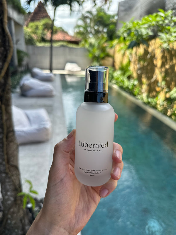 A photo of a hand holding a bottle of natural lubricant by the pool in Bali